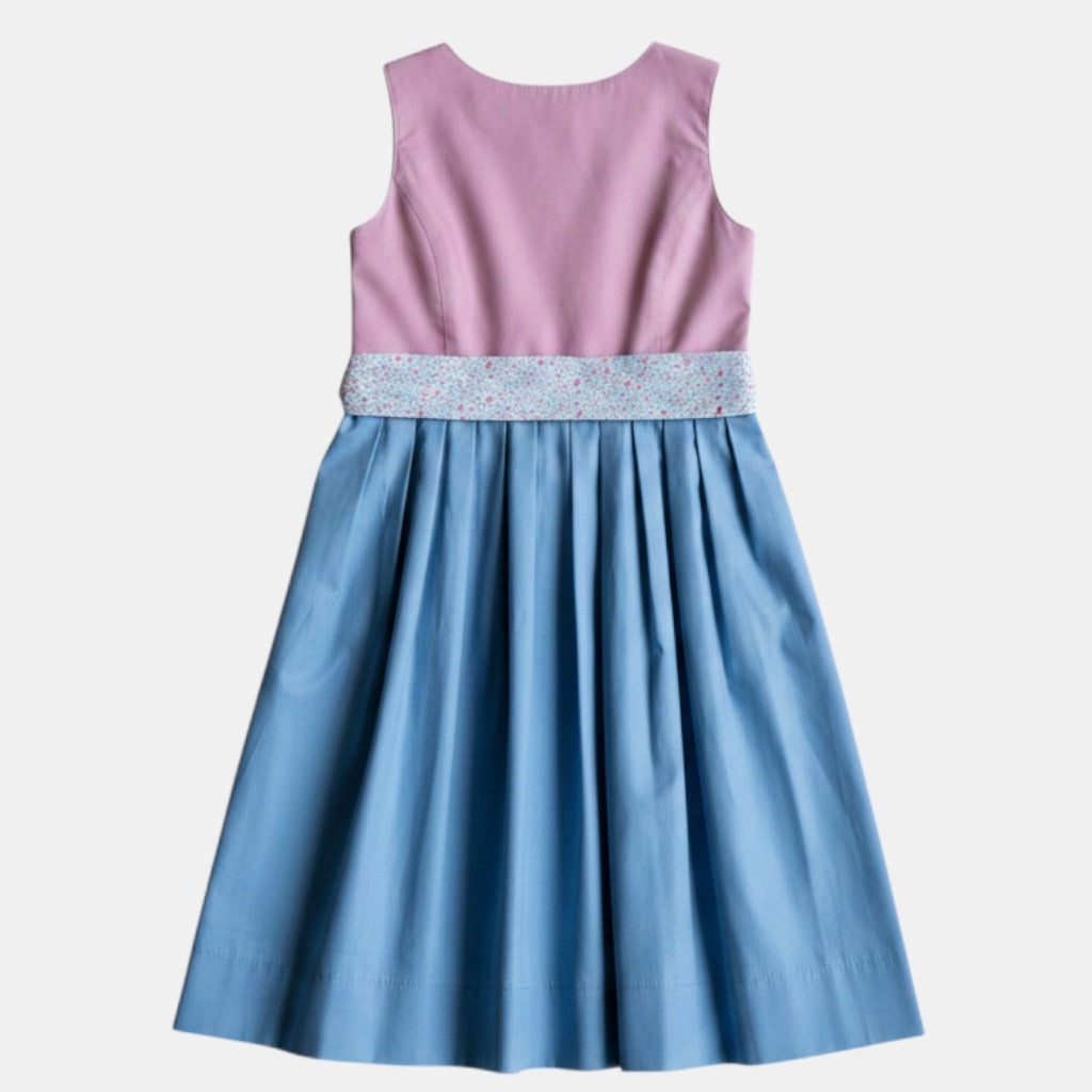 Kinderdirndl Blush Rosa mit Blumenmuster und blauem Rock vor freigestelltem neutralem Hintergrund von hinten