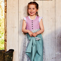 Kinderdirndl fliederfarben mit salbeifarbener Schürze und blumigem Rock, klassische Wiener Naht, getragen von einem Mädchen mit Zöpfen