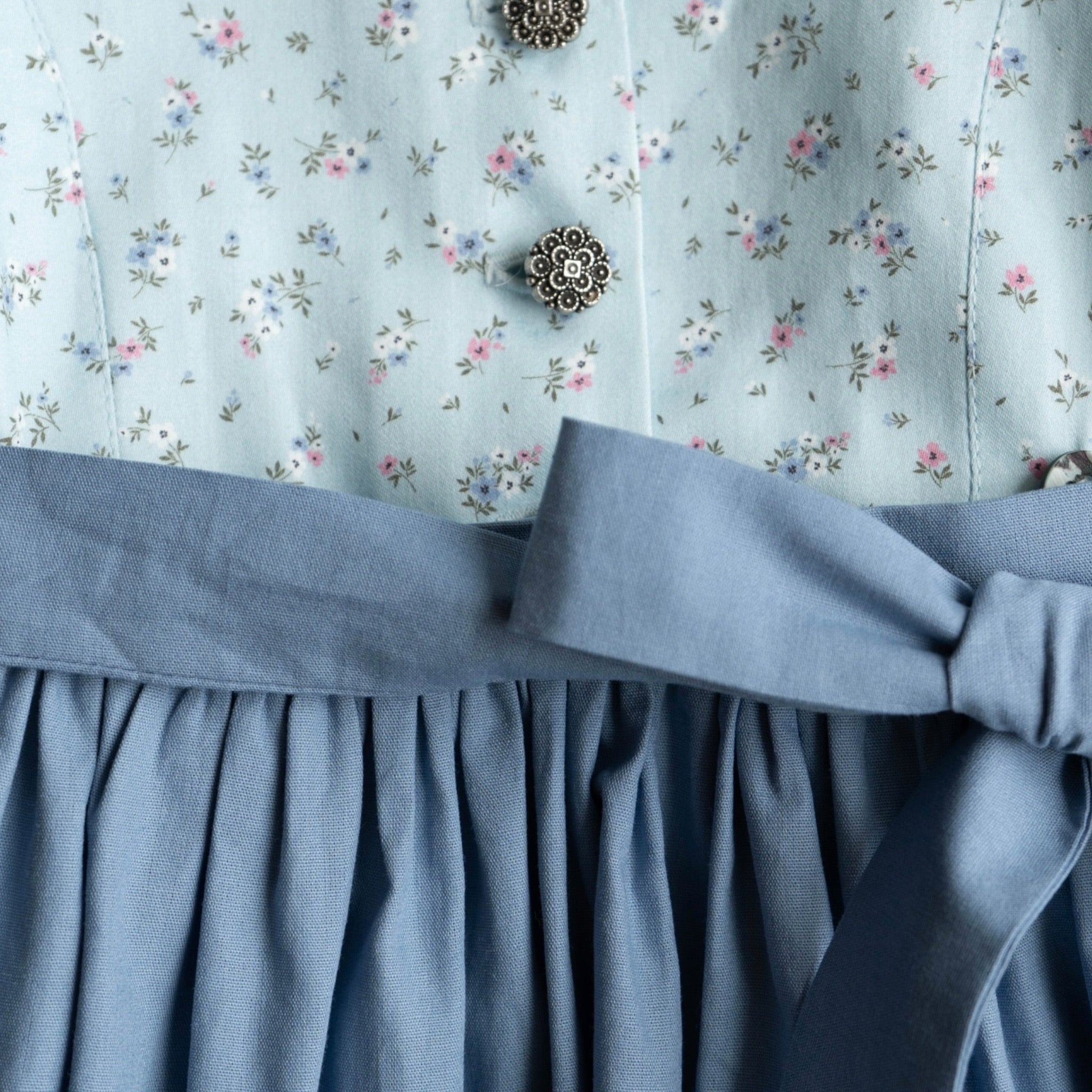 Kinderdirndl hellblau mit blauer Schürze in Detailansicht