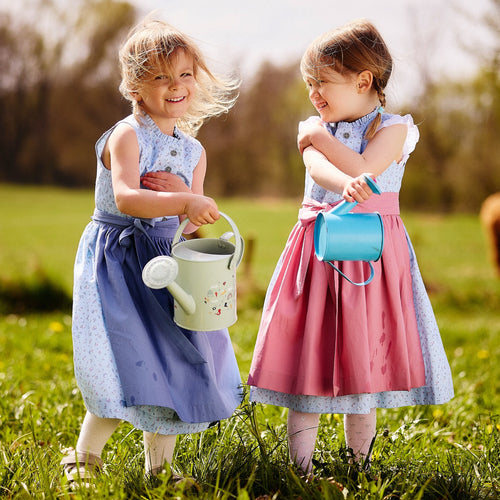 Kinderdirndl in hellblau getragen von zwei Mädchen mit blauer und altrosa Schürze auf einer Wiese