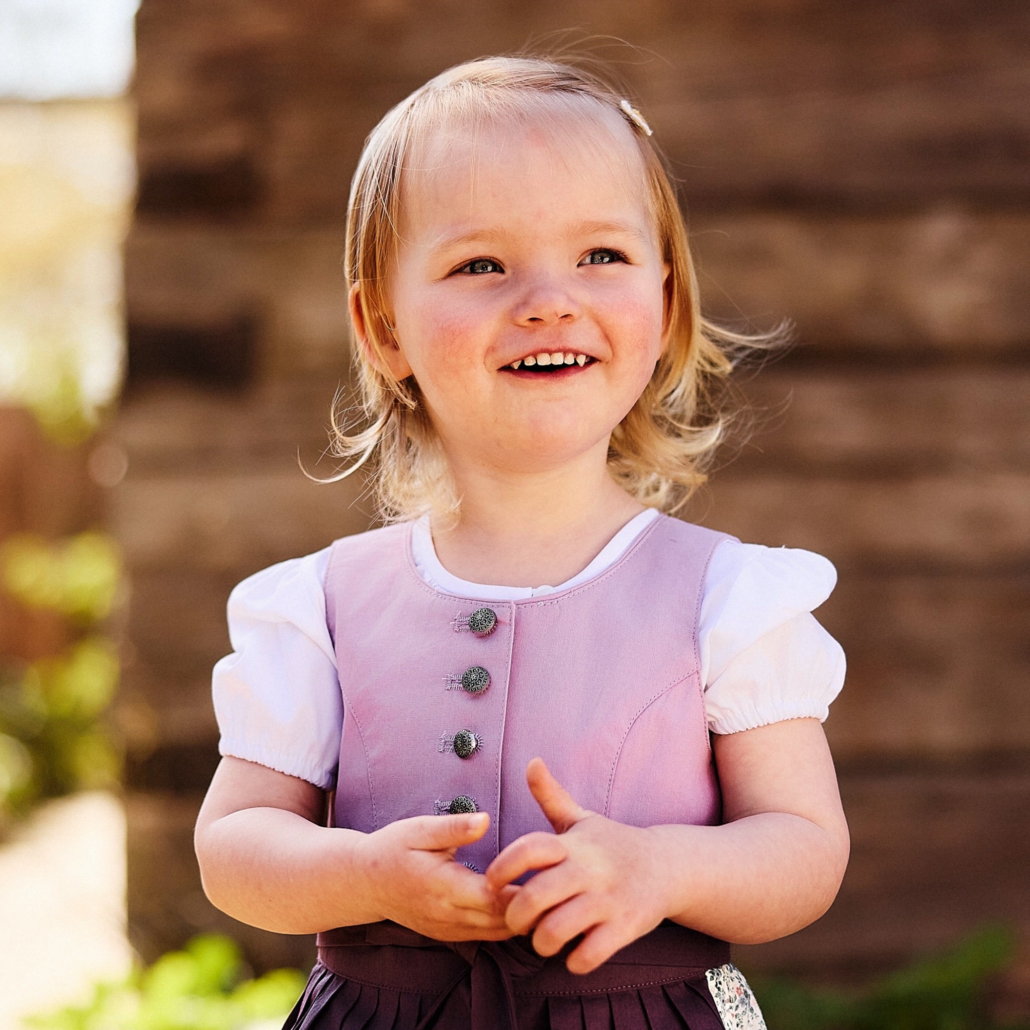 Kinderdirndlbluse kurzärmlig mit klassischen Puffärmeln und mit T-Shirt Schnitt getragen zu einem flieder Kinderdirndl